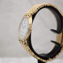 Angled side view of the gold Raymond Weil watch showing the crystal-set bezel, crown, and integrated bracelet.