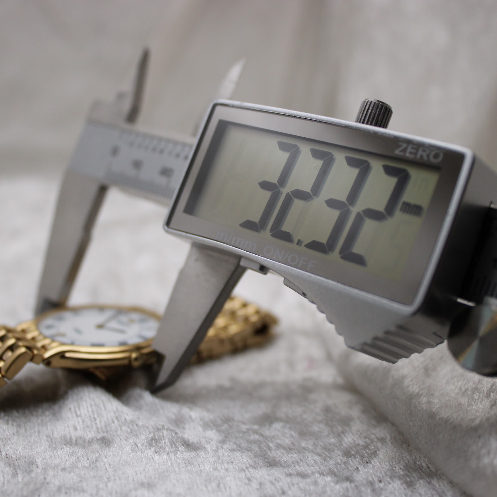 Digital caliper measuring the case diameter of the gold Raymond Weil watch, displaying 20.09mm.