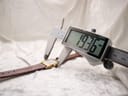 Digital caliper measuring the width of the Raymond Weil watch case from the side, displaying an exact measurement of 19.36 mm.