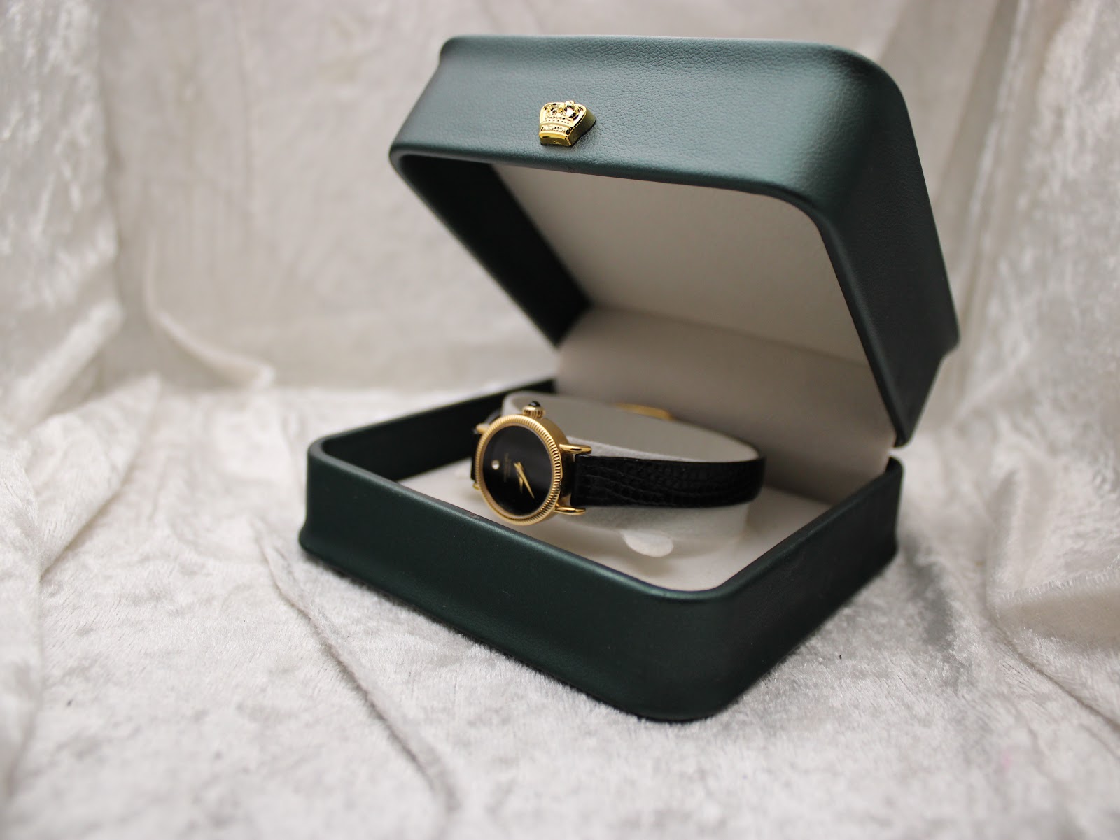 The Raymond Weil 544 watch resting in a dark green presentation box with a gold crown emblem.