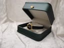 The Raymond Weil 544 watch resting in a dark green presentation box with a gold crown emblem.