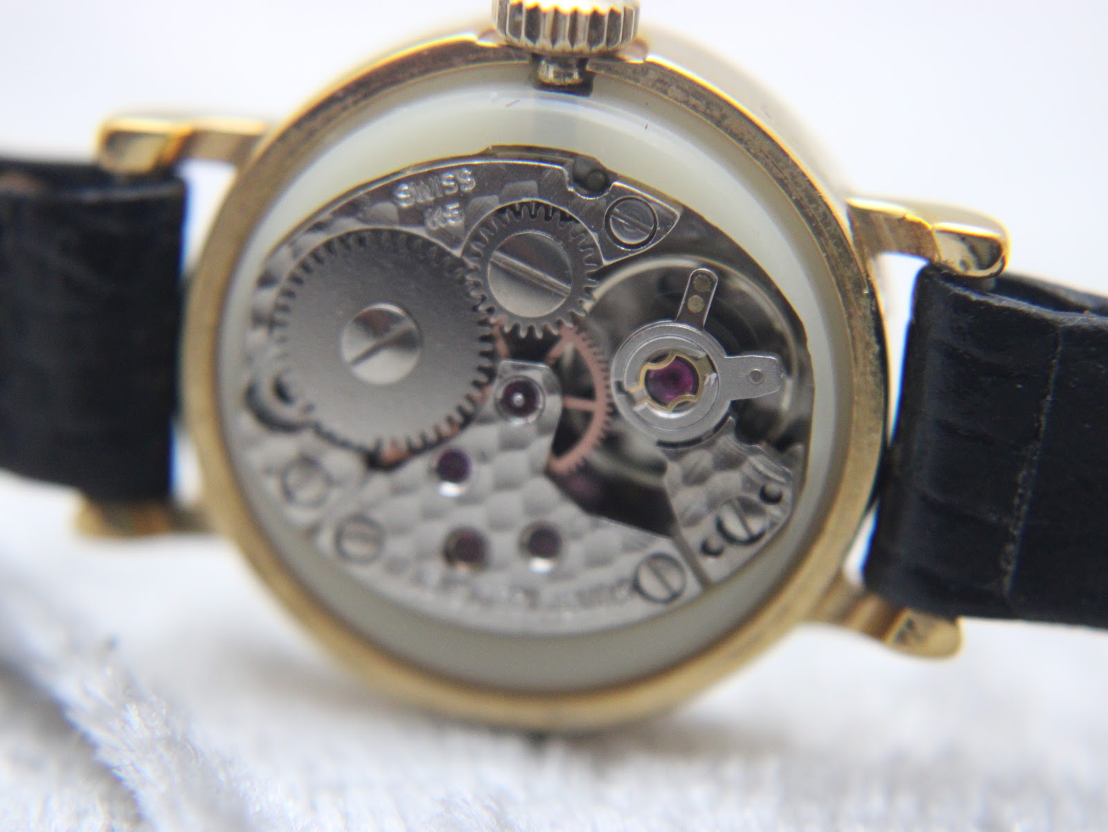 Macro view of the Swiss manual wind mechanical movement inside the Raymond Weil watch, showing gears and jewels.