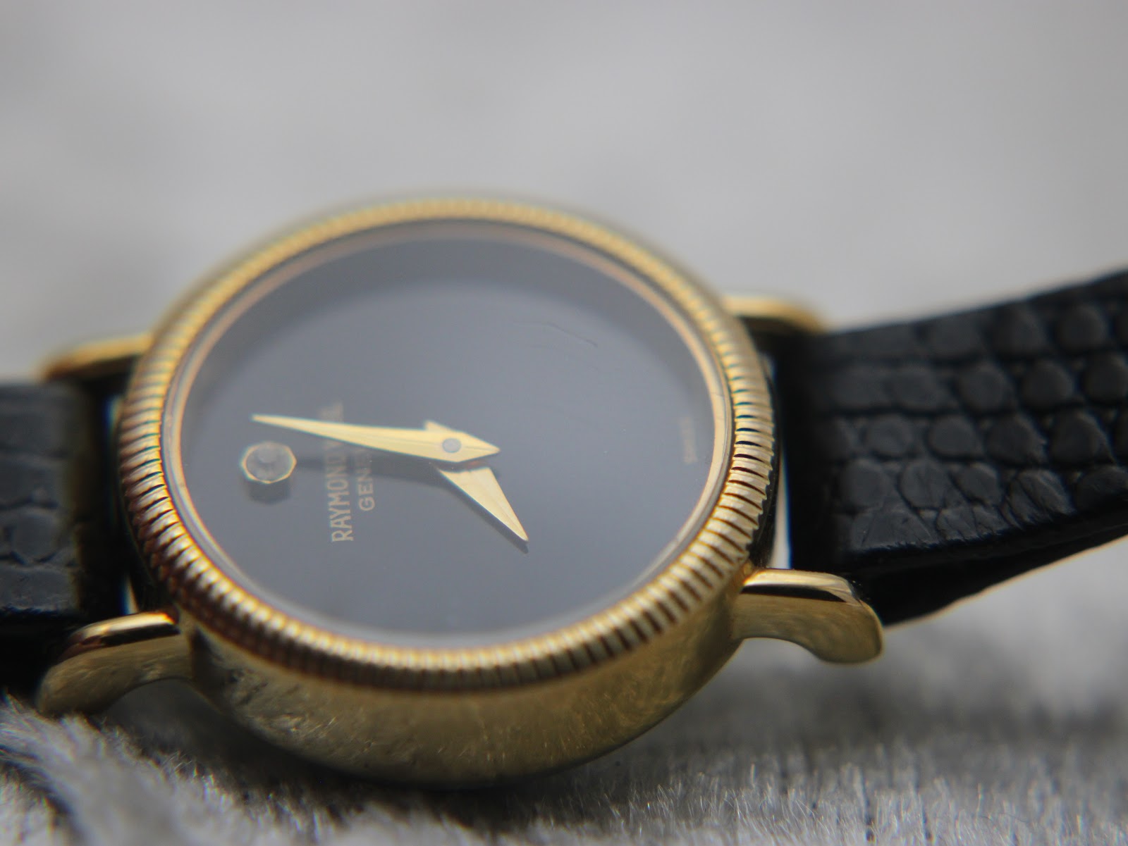 Close-up of the watch dial and gold case bezel from a slightly different angle, showing the ridged texture of the bezel.