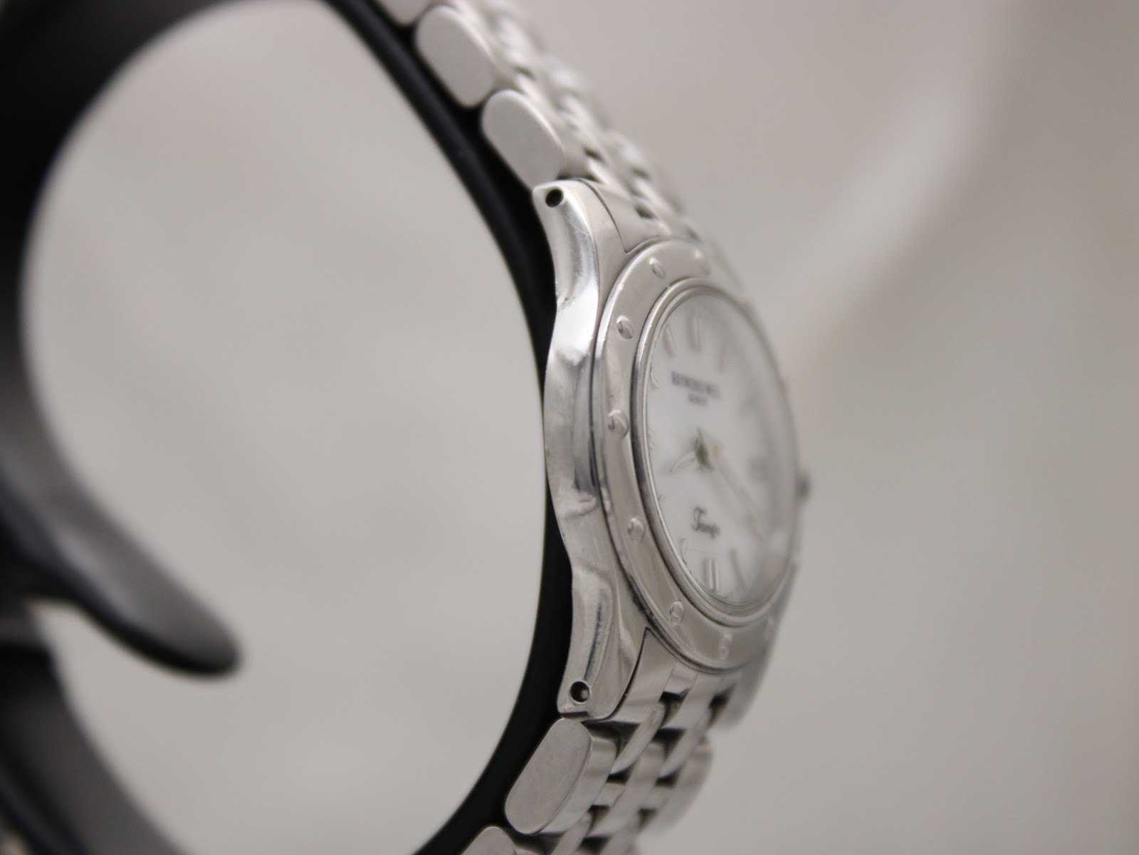 Side view of the Raymond Weil Tango watch, focusing on the sleek lines of the stainless steel case and integrated bracelet from the left side.