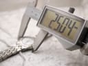 Close-up of a digital caliper measuring the watch case, displaying a precise diameter of 25.04 mm.