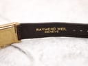 Close-up of the underside of the brown crocodile leather strap showing "RAYMOND WEIL GENEVE" embossing