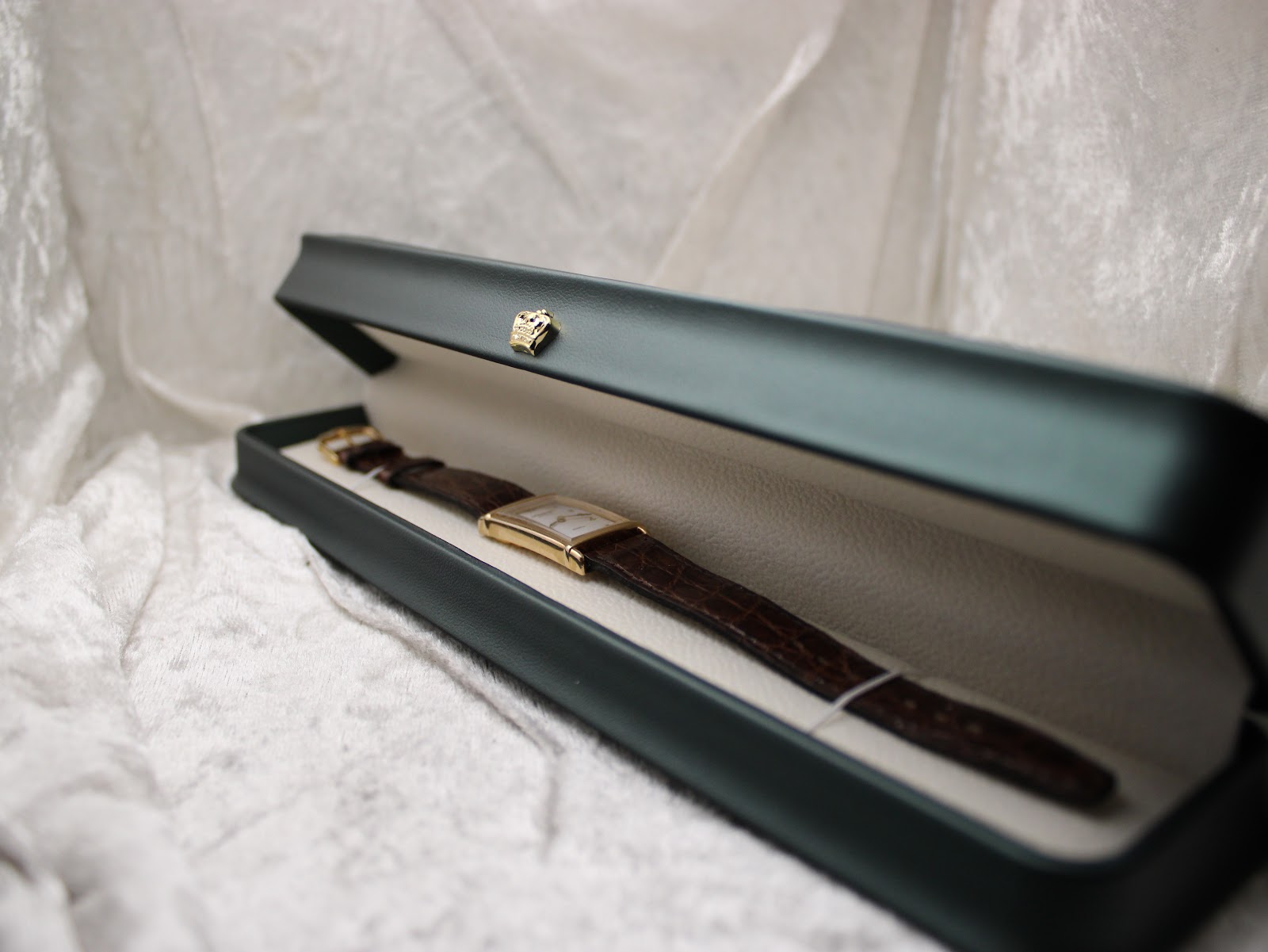 Full view of the Raymond Weil watch inside an open dark green watch presentation box with light interior