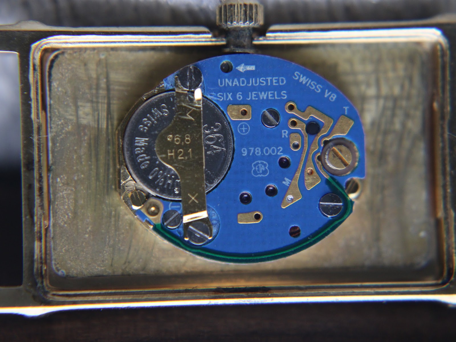 Close-up of the watch movement with the case back removed, showing the Swiss ETA 978.002 quartz movement and battery