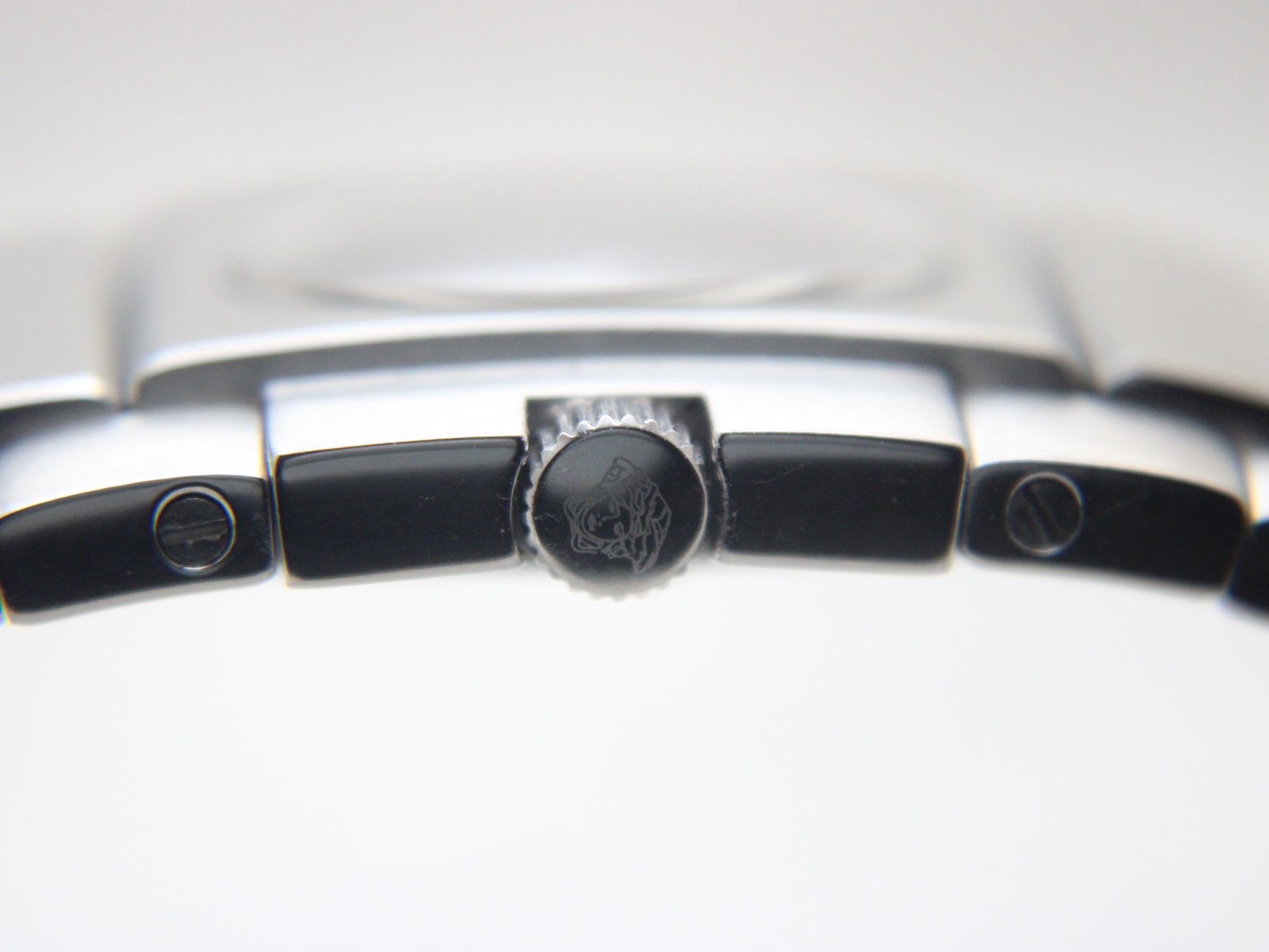 Extreme close-up of the Medusa head logo engraved on the watch's crown.