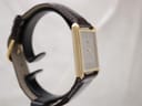 Other side profile view of the gold-tone rectangular Seiko watch on a display stand, showing the left side of the case.
