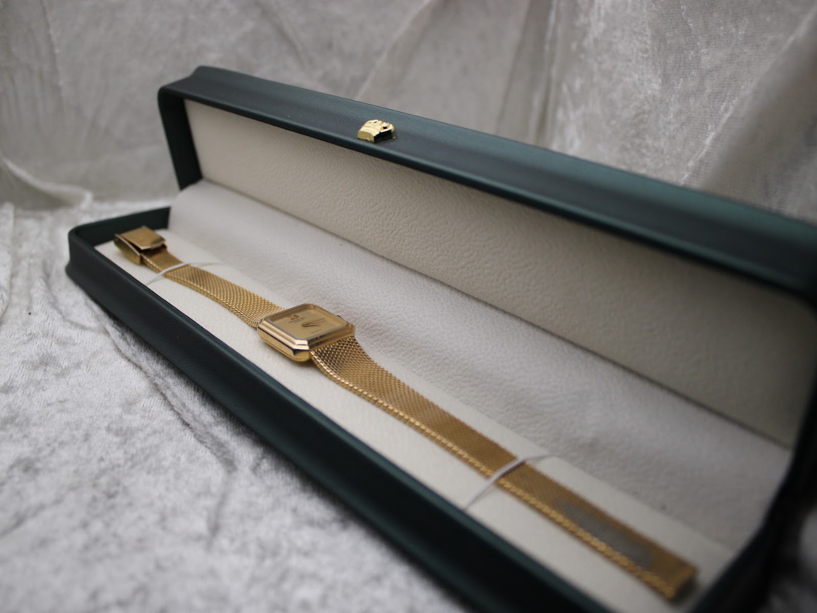 The gold watch displayed neatly inside a dark green LWM presentation box.
