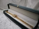 The gold watch displayed neatly inside a dark green LWM presentation box.