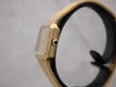 Side view of the gold-plated watch showing the cabochon crown with black inset stone.