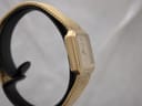 Another side view of the gold-plated watch, highlighting the slim profile and mesh bracelet texture.