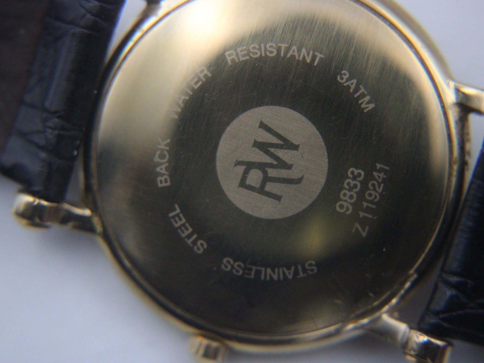 Another close-up of the Raymond Weil watch case back, focusing on the "RW" logo and engraved details.
