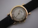 Close-up of the cream dial of the Raymond Weil watch, showing Roman numerals, baton indices, and gold-tone hands.