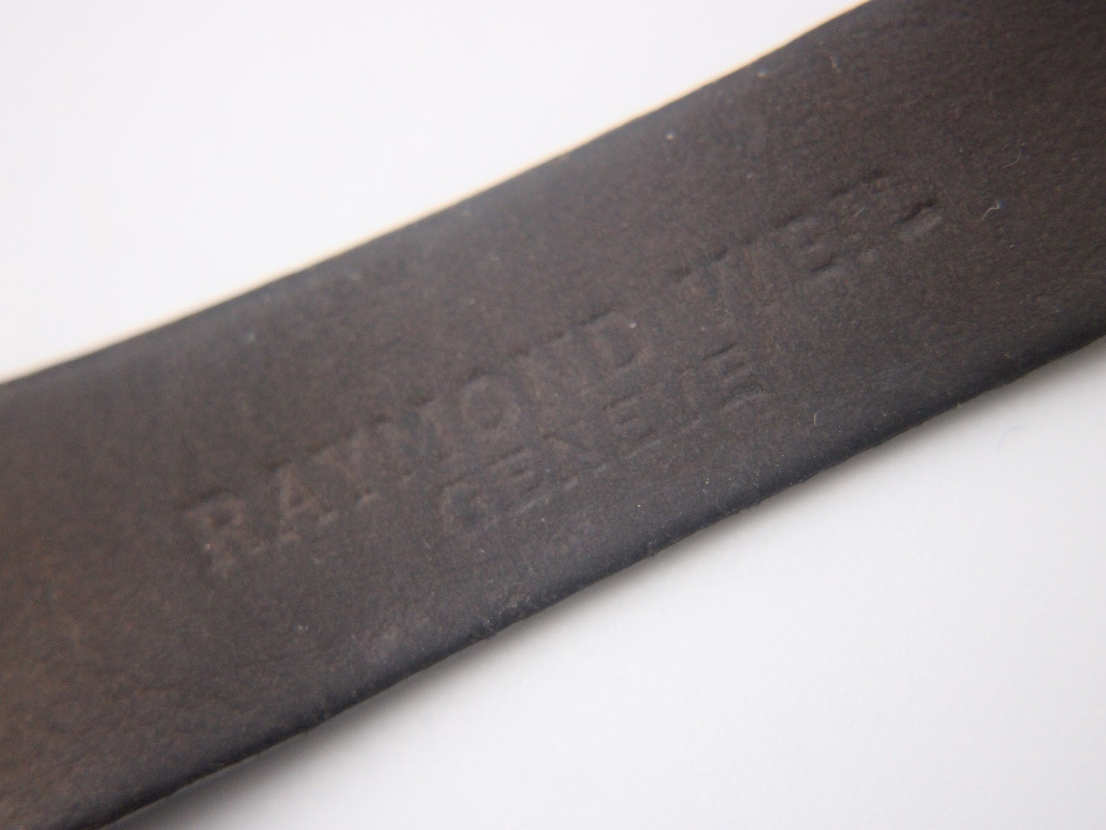 Close-up of the black leather strap's underside, revealing the "RAYMOND WEIL GENEVE" embossing.