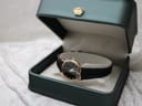 Raymond Weil watch displayed inside a deep green watch box with a gold crown emblem on the lid.