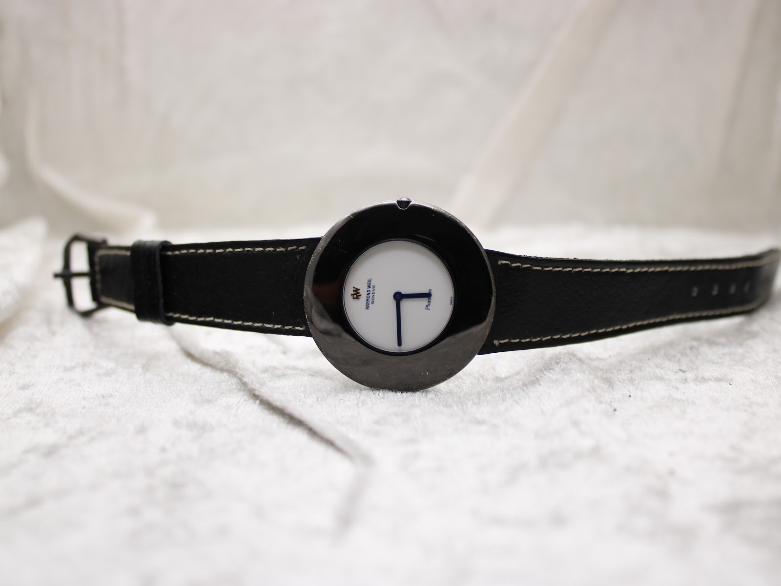 Overhead view of the Raymond Weil Phantôm watch lying flat with its black leather strap extended.