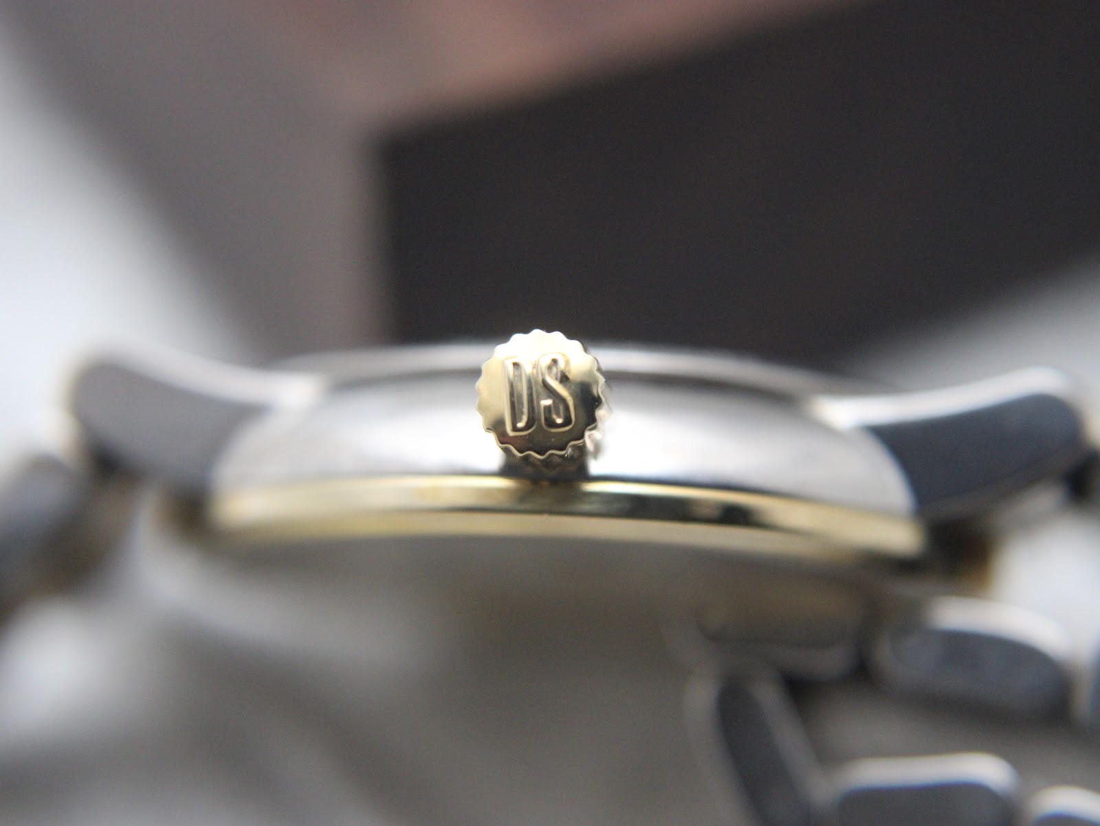 Detailed close-up of the gold-tone crown of the Certina DS Caimano, clearly showing the "DS" logo.