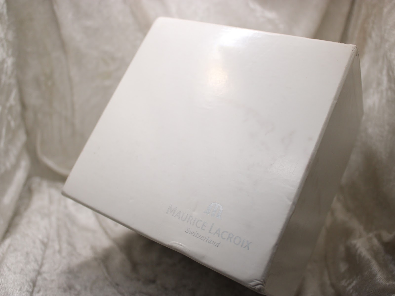 The white outer cardboard box for the Maurice Lacroix watch, with brand logo.