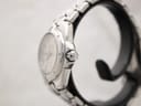 Side view of the Tissot PR 200 watch on a stand, highlighting the signed "T" crown and curved stainless steel case.