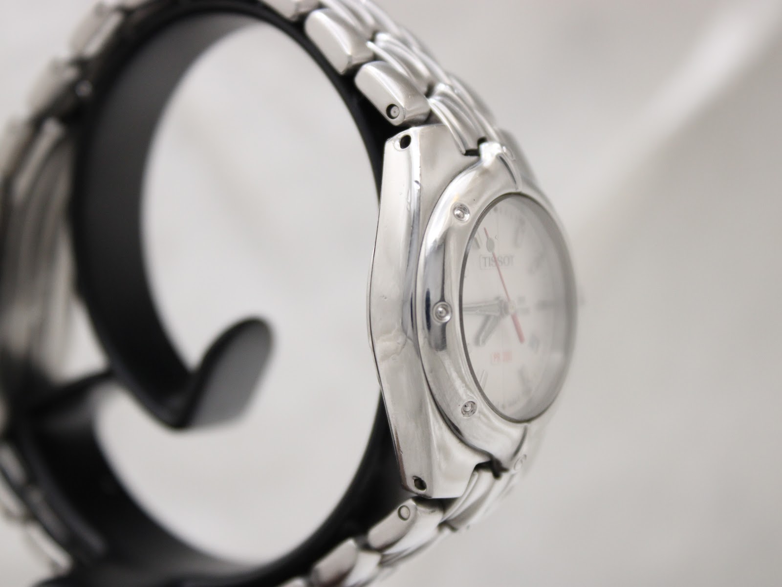 Another side view of the Tissot PR 200 watch on a stand, showing the case profile and integrated bracelet links.