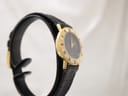 Close-up of signed Gucci gold buckle on black leather strap.