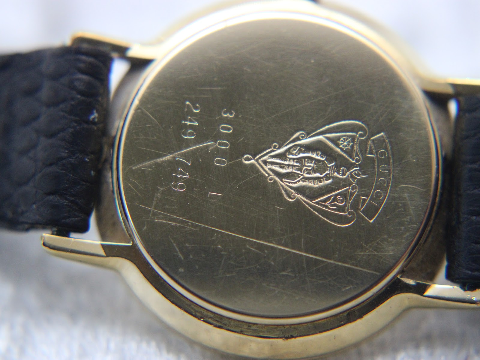 Detailed view of the black dial with gold Roman numerals and hands.