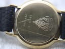 Detailed view of the black dial with gold Roman numerals and hands.