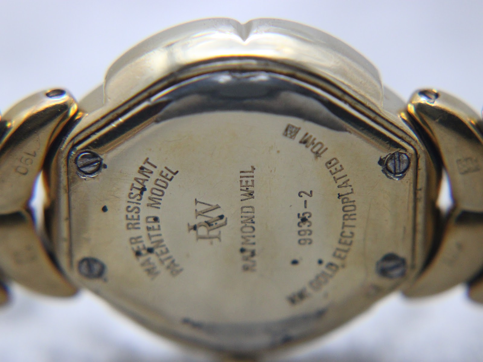 Close-up of the Raymond Weil Adagio watch case back, showing "Water Resistant - Patented Model", "RW Raymond Weil", "9935-2" and "18K GOLD ELECTROPLATED 10M".