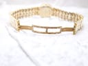 View of the hidden clasp on the integrated gold-electroplated bracelet, open and lying on a white textured surface.
