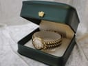 The Raymond Weil Adagio watch sitting inside a dark green presentation box with a gold crown emblem, showcasing the watch and its integrated bracelet.