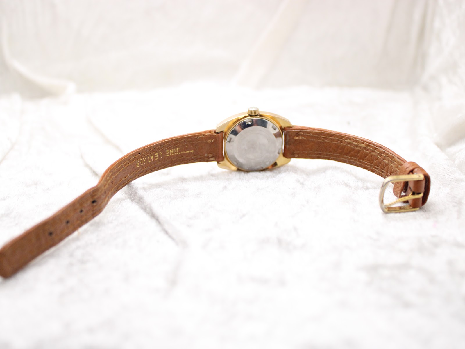 Back view of the Bulova watch and its brown leather strap, showing "GENUINE LEATHER" text on the strap.