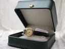 The Raymond Weil watch nestled inside an open dark green watch box with a gold crown emblem on the lid.