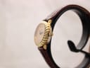 Side profile view of the Raymond Weil 683 watch on a stand, highlighting the fluted gold-tone bezel and original gold-tone crown.