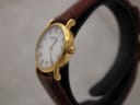Right side view of the Raymond Weil 9923 watch, highlighting the gold electroplated case, fluted crown, and brown leather strap.