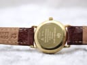Close-up of the gold-tone case back of the Raymond Weil 9923, engraved with model number, water resistance, and "18K Gold Electroplated", and "12" on the strap end.