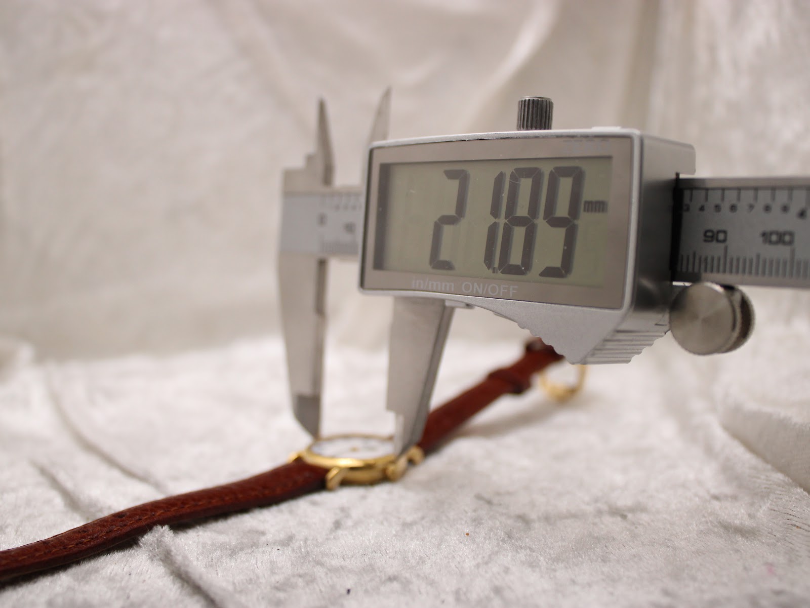 A digital caliper measuring the case diameter of the Raymond Weil 9923, displaying a precise reading of 21.9mm.