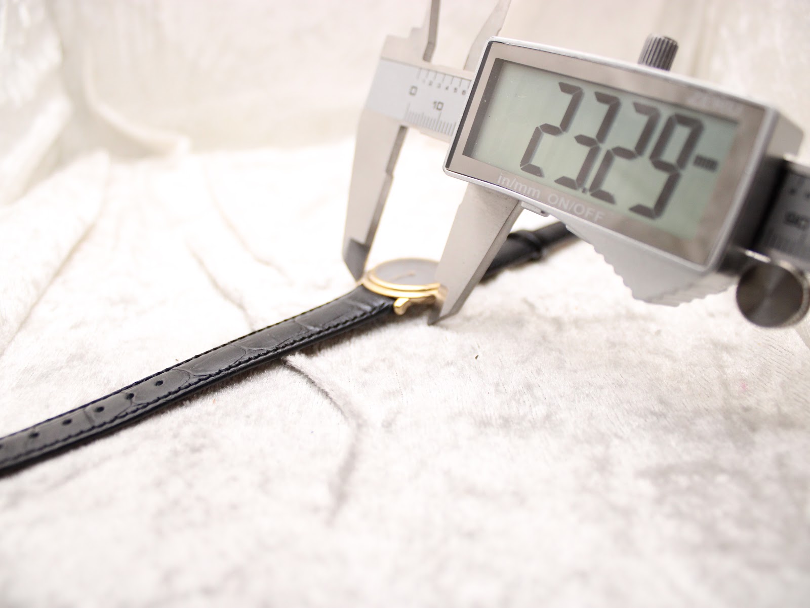 Digital caliper measuring the watch case diameter at 23.29mm, showing the slim profile.