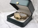 The Raymond Weil watch presented inside a dark green watch box, highlighting its gold aesthetic.
