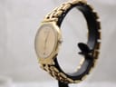 Side view of the gold-tone Raymond Weil watch displayed on a watch stand, showing its slim profile and small crown.