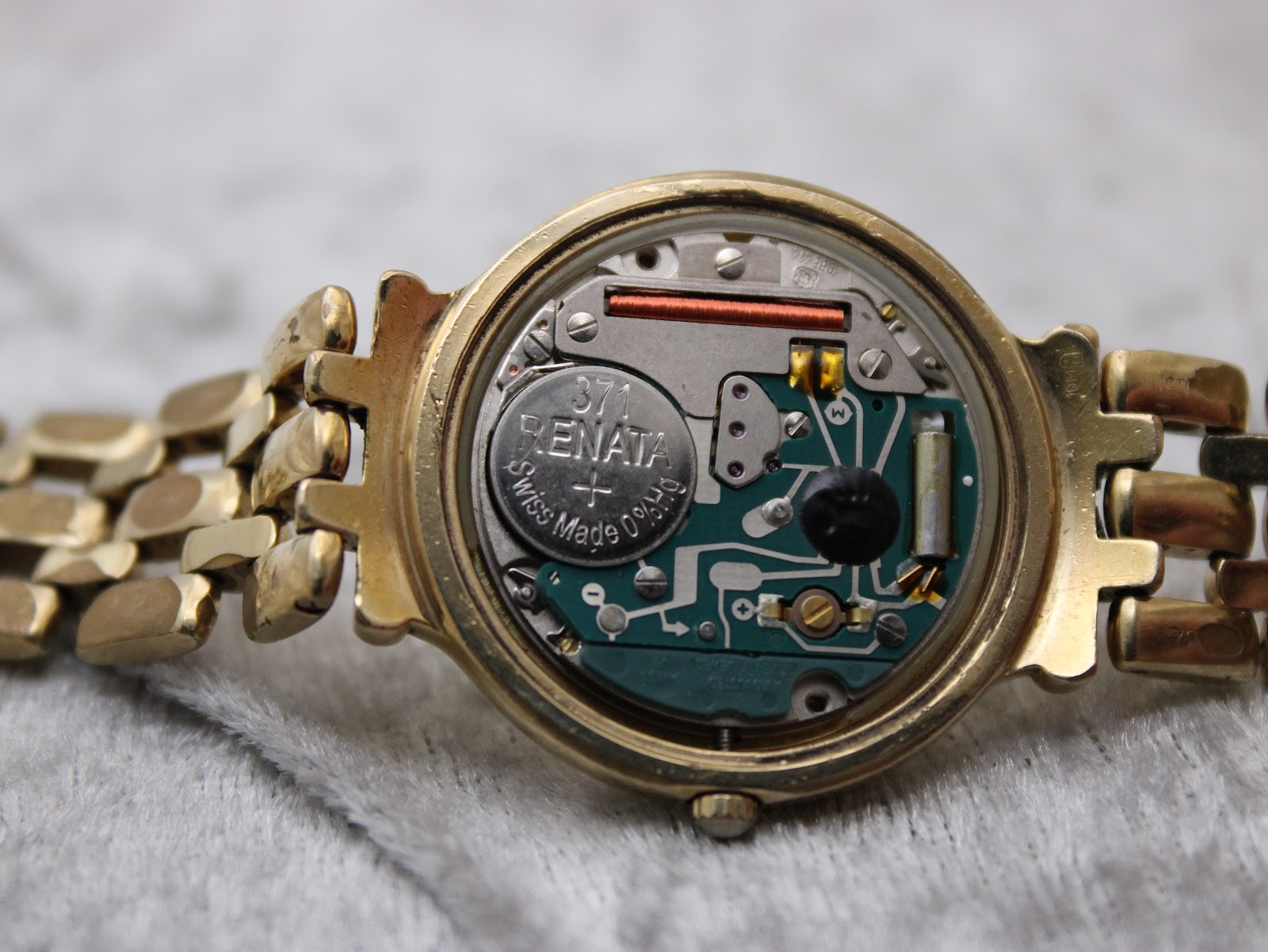 Close-up of the opened case back revealing the Swiss quartz movement with a Renata 371 battery installed.
