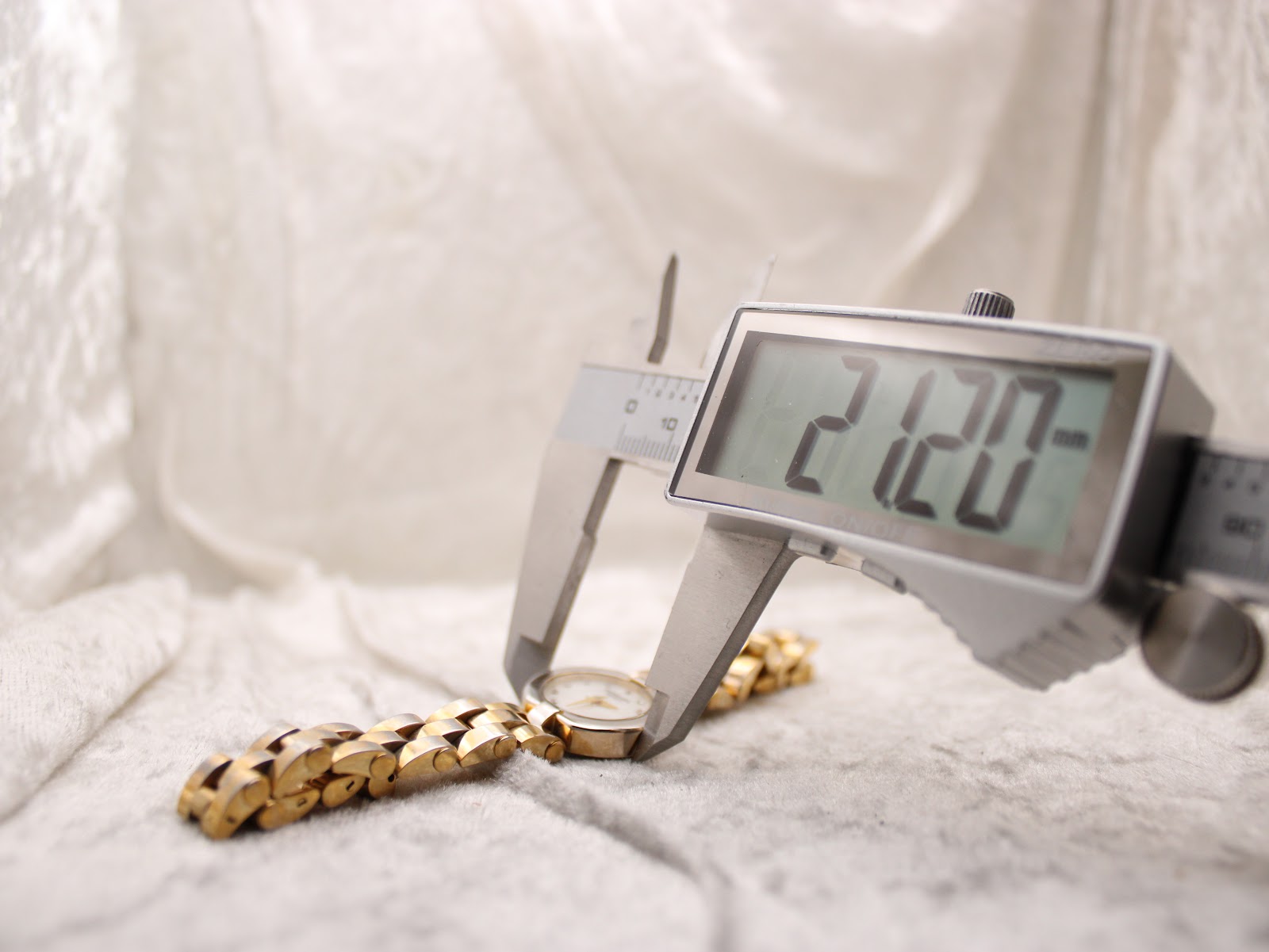 Digital caliper measuring the watch case diameter, displaying 21.20mm