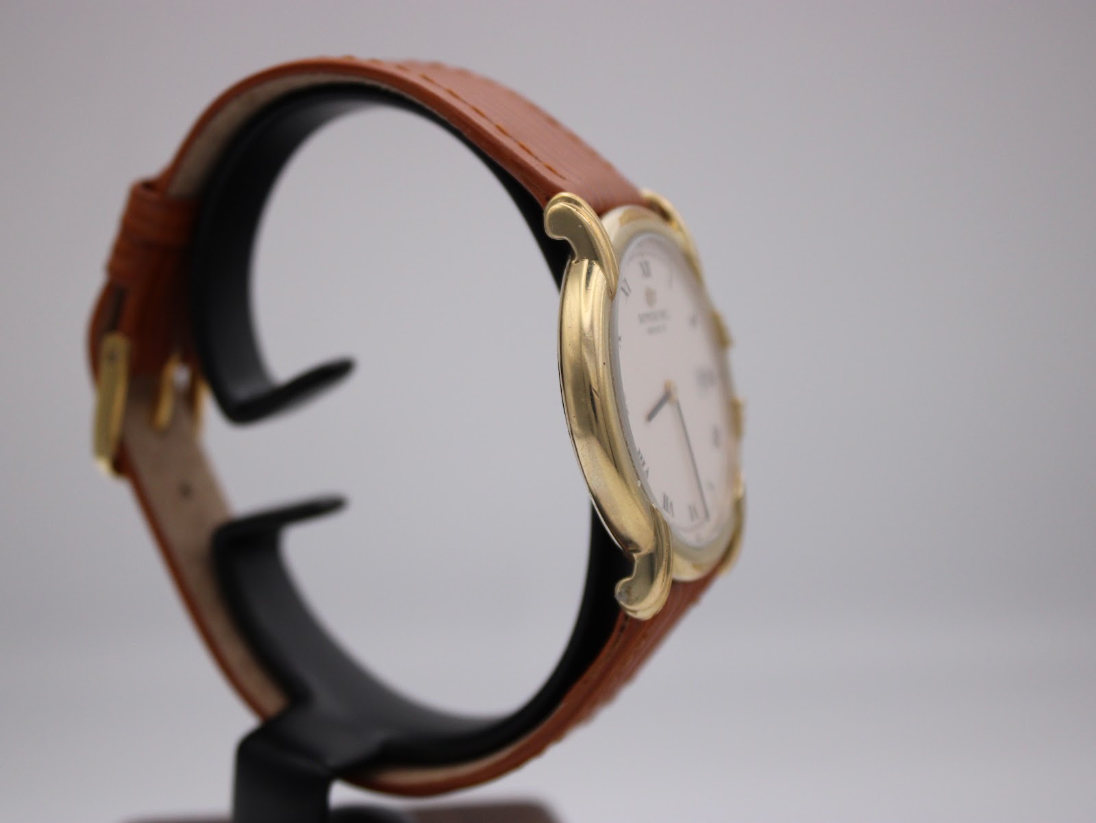 Angled side view of the Raymond Weil 9155 watch showing the curved case and textured brown leather strap.