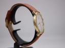Angled side view of the Raymond Weil 9155 watch showing the curved case and textured brown leather strap.
