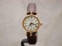Front view of gold-plated Gucci 2000L watch with ivory Roman numeral dial and burgundy leather strap.