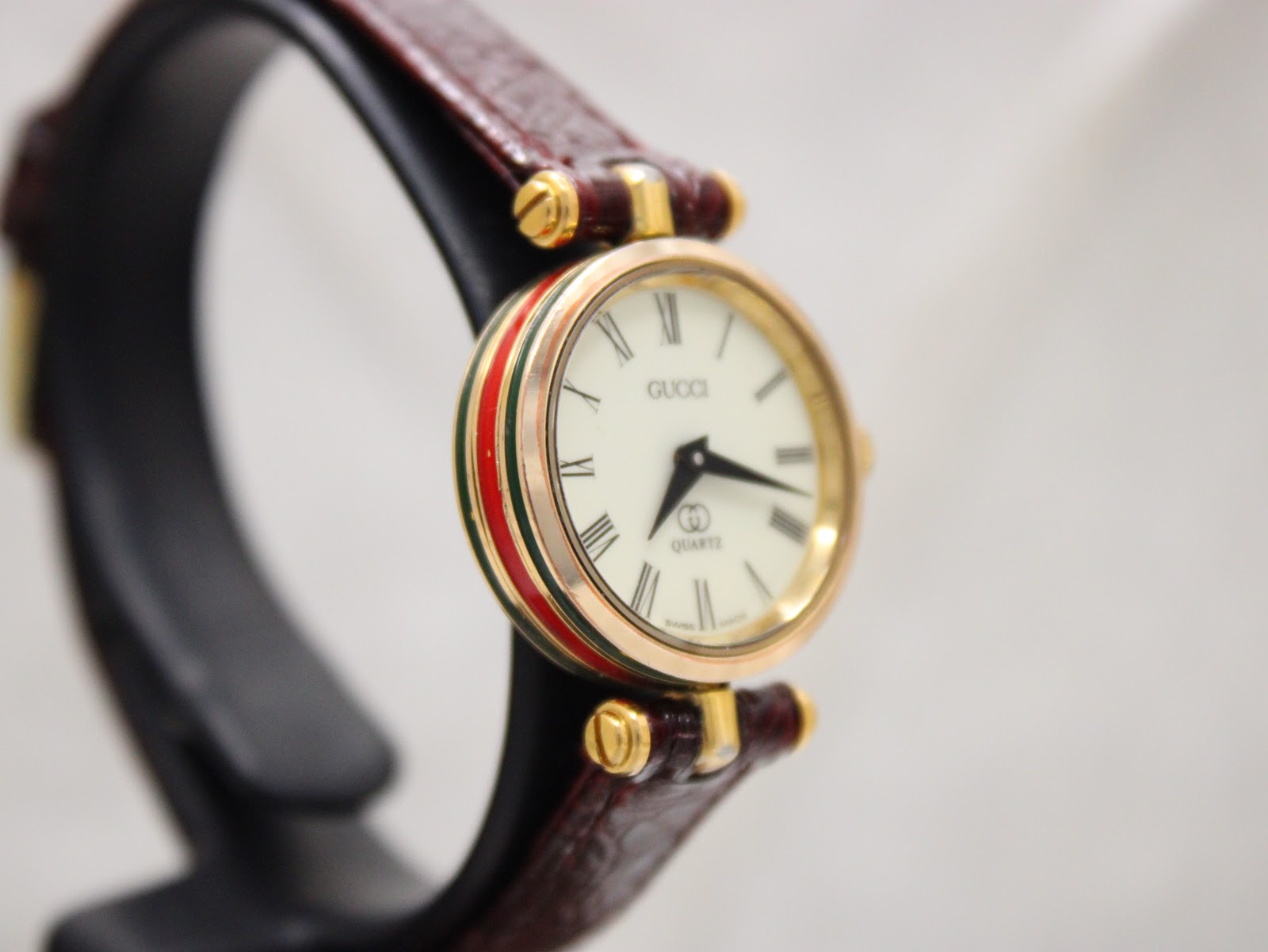 Another angled side view of the Gucci 2000L, highlighting the green and red case stripe and the gold-plated finish.