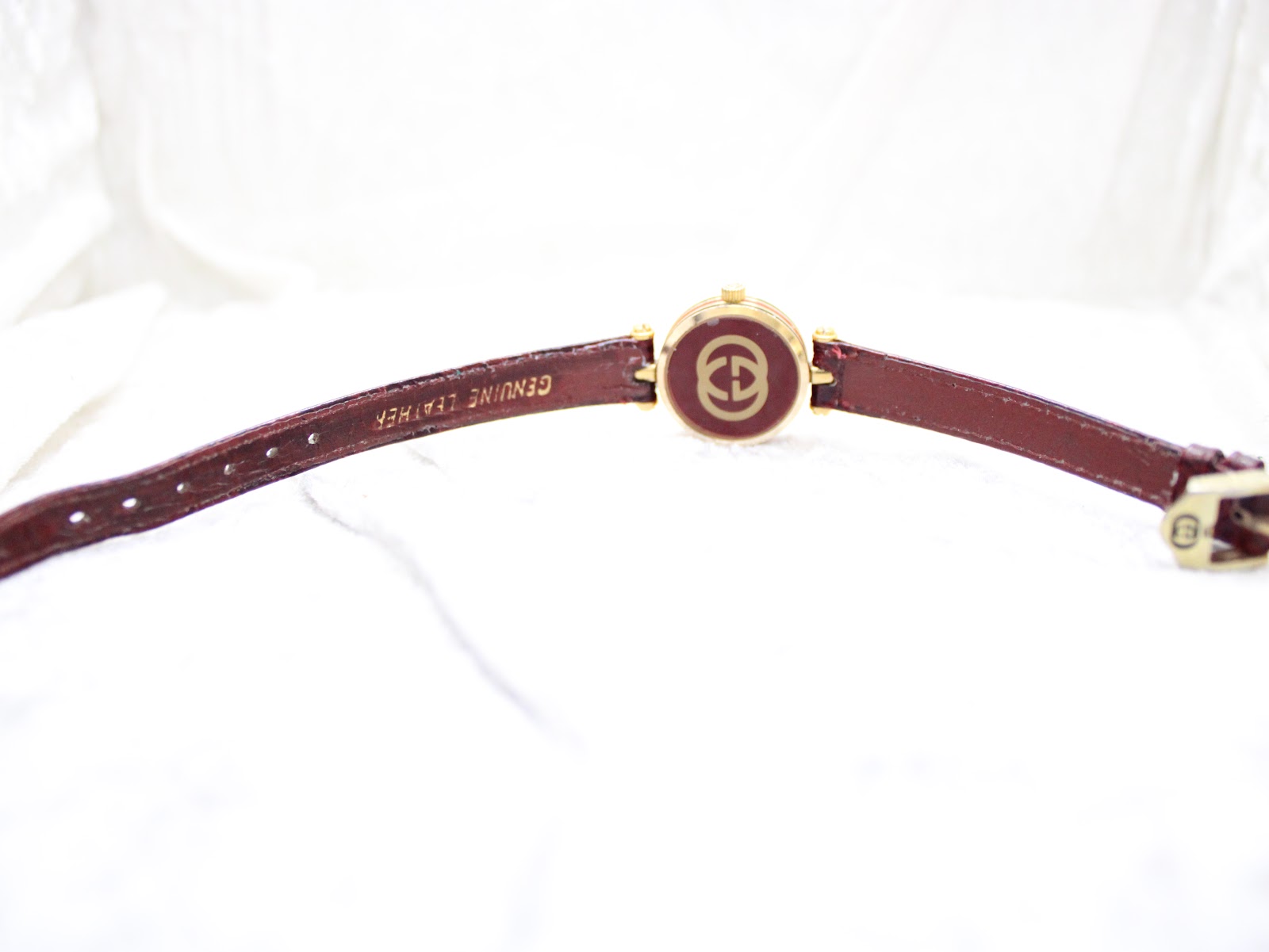 View of the Gucci 2000L from the back, showing the underside of the burgundy leather strap and the gold-toned case back with GG logo.