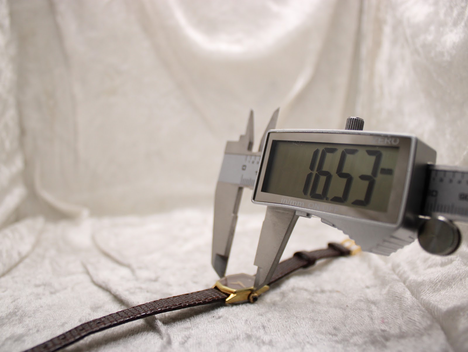 Digital caliper measuring the case diameter of the watch, displaying a reading of "16.53 mm" excluding the crown.